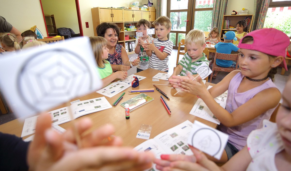 Kinder basteln unter Anleitung an Tischen