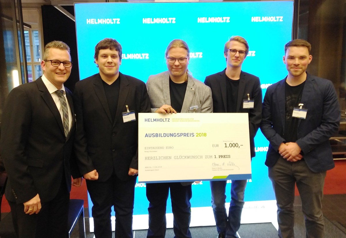 Gruppenbild des Siegerteams mit großer Urkunde vor blauem Helmholtz-Bildschirm