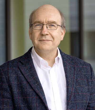 Portrait von Markus Diesmann vor einem Regal mit Büchern im Hintergrund.