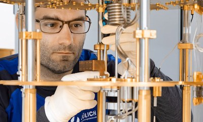 Eine Person mit Brille und Handschuhen arbeitet an einem komplexen Gerät mit metallischen und gläsernen Komponenten. (Mistral: Pixtral Large 2411, 2026-03-04)