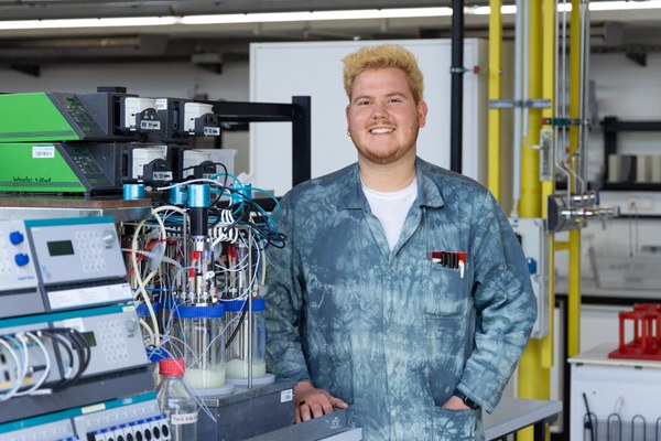 Christian Wagner steht in einem blauen Batik-Laborkittel in seinem Labor und lächelt freundlich in die Kamera.