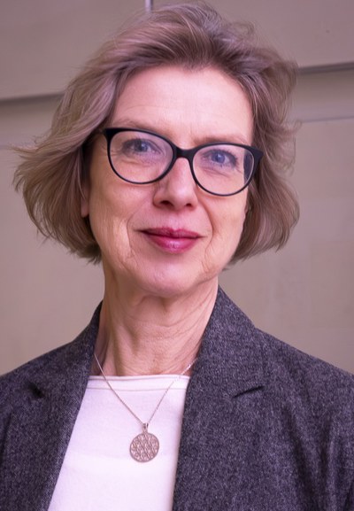 Das Foto zeigt Anne Rother vor einem hellen Hintergrund, die direkt in die Kamera lächelt.