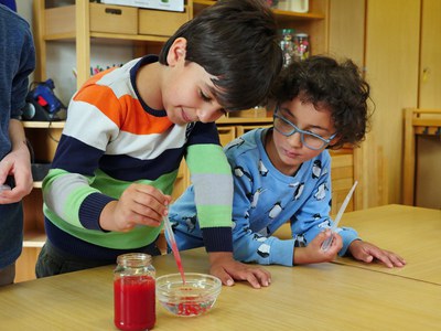Die kleinen Forscher tröpfeln mit Pipetten die rote Alginat-Lösung in die Schälchen mit Calcium-Lösung und lassen bunte Gelkapseln entstehen. 