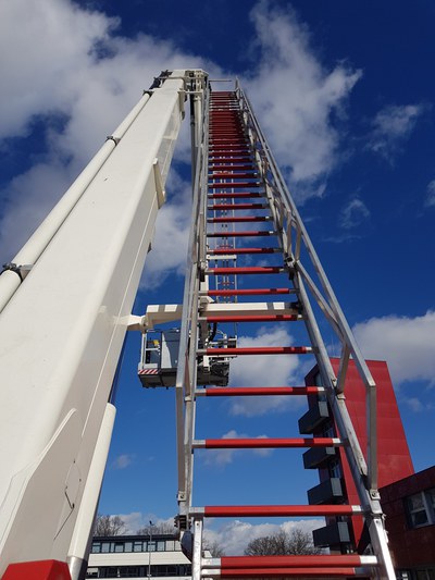 Eine ausgefahrene Teleskopmastbühne vor blauem und leicht bewölktem Himmel.