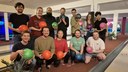 Mehrere Personen posieren lächelnd in einer Bowlinghalle, einige halten Bowlingkugeln in den Händen. (Mistral: Pixtral Large 2411, 2026-03-17)
