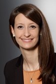 Eine lächelnde Person mit langen Haaren vor einem neutralen Hintergrund. (Mistral: Pixtral Large 2411, 2026-03-04)