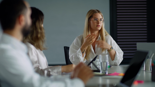 An employee exchanges ideas with her colleagues in a meeting.