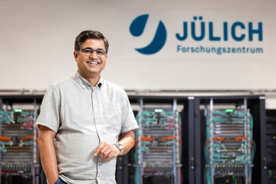 A colleague stands in a hall. Computers can be seen in the background.