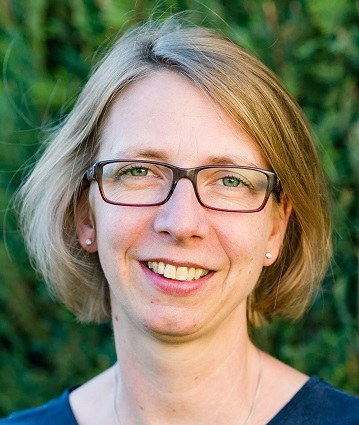 A person with short hair and glasses smiling in front of a blurred green background. (Mistral: Pixtral Large 2411, 2026-05-29)