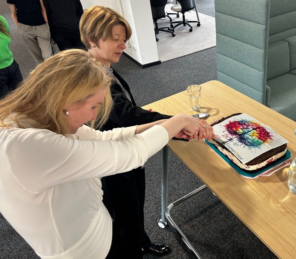 A woman in white leans over a table to touch a decorated cake while another woman watches. (Mistral: Mistral Medium 3.5, 2026-06-29)